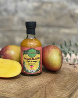 Nicolas Alziari Mango Essig in Glasflasche mit frischen Mangos auf Holztisch