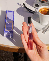 Panier des Sens Eau de Toilette Lavendel aus der Provence 10ml in der Hand gehalten neben Verpackung, Espressotasse und Kamera in stilvoller Lifestyle-Atmosphäre im Freien