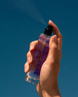 Panier des Sens Eau de Toilette Lavendel aus der Provence 50ml bei der Sprühanwendung mit feinem Duftnebel vor blauem Himmel in natürlicher provenzalischer Atmosphäre