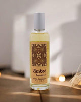 Provence et Nature Raumduftspray Amber auf Holztisch mit warmen Lichtern im Hintergrund